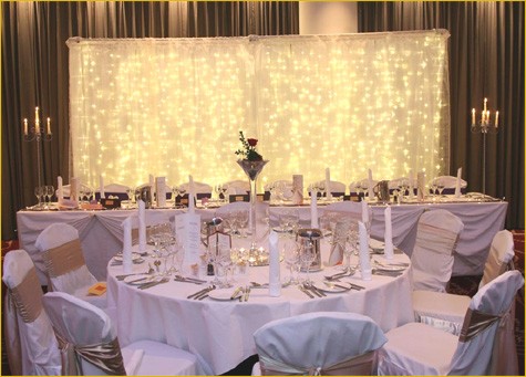 White linen table cloth. White chair covers & pink sash tied in a bow
